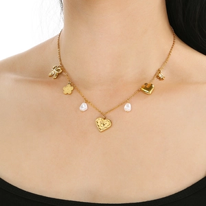 Elegant gold titanium steel necklace with heart, bow, and pearl pendants on a model