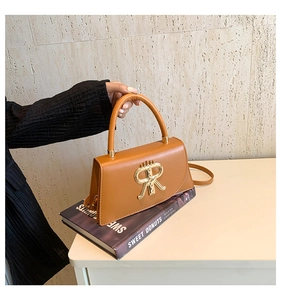 Close-up of caramel PU leather handbag with golden R-shaped buckle and top handle detail