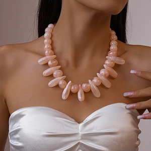 Detail of light pink acrylic marbled beads and teardrop pendants on a choker necklace