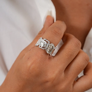 Gros plan détaillé d'une bague fleur de rose géométrique argentée au doigt