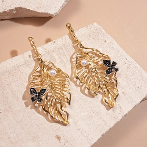 Golden hollow leaf earrings with pearl and butterfly on a natural stone base