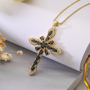 Macro shot of 18K gold-plated cross pendant with black gemstones and box chain necklace