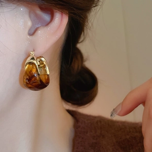 Close-up of vintage amber resin U-shaped earrings on model for a retro autumn style