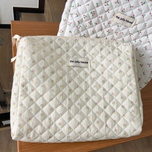 Detail of floral and cherry quilted cotton makeup bags with The Jolly House logo label