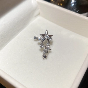 Détail macro du耳cuff argenté en forme d'étoile avec zircons brillants dans sa boîte