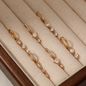 Elegant gold earrings set with zircon stones displayed in a luxury wooden jewelry box