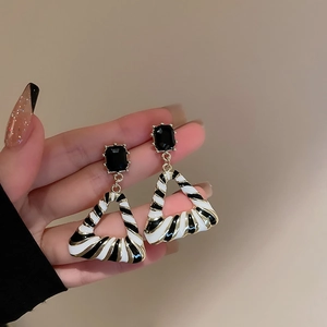 Detail of vintage geometric triangle earrings with gold plating and leopard enamel inlay