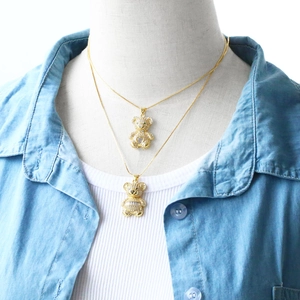 Detail of layered gold bear necklaces with pave cubic zirconia and green heart stone