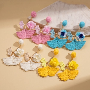 Detail of raffia woven flower earrings in pink, blue, white, and yellow on marble