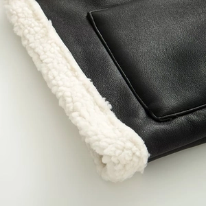 Detalle de costura de cuero negro con forro de sherpa blanco en un chaleco de otoño