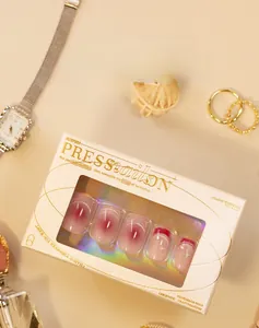 Detail of pink gradient press-on nails with small rhinestones in gold branded box