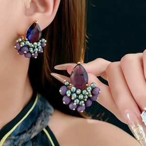 Macro shot of vintage style earrings with purple water-drop gems and beaded accents