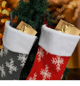 Close-up of plush Christmas stockings with white snowflake patterns on a tree branch
