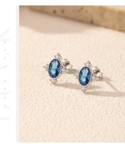 Detailed close-up of s925 silver stud earrings featuring oval blue gemstones and white crystals
