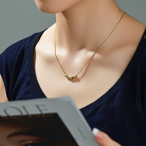 Minimalist 14k gold-plated snake chain necklace featuring three oval bead pendants on model