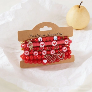 Detalle de pulseras de cuentas rojas con colgantes de corazón en tarjeta kraft