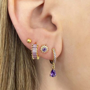 Detail of model wearing gold hoop earrings set with purple zircon and sunflower stud