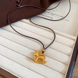Pendentif cheval à bascule plaqué or avec cordon marron dans un coffret à bijoux chic