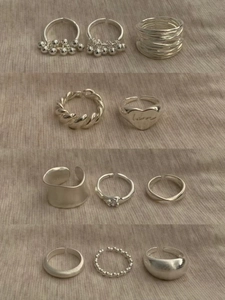 Macro shot of 11 assorted silver rings featuring beaded tassels and heart engravings