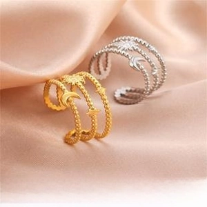 Detail of sun and moon charms on beaded layered stainless steel rings on silk