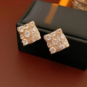 Gros plan de boucles d'oreilles carrées plaquées or avec zircons sur une boîte à bijoux noire