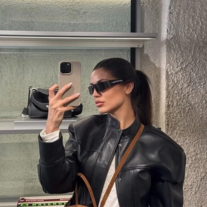 Dettaglio di giacca biker in pelle nera con collo alto e occhiali da sole moda