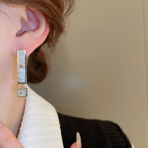 Detailed close-up of asymmetrical zircon drop earrings with elegant silver finish