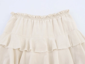 Detail of high waist ruffled midi skirt with elastic smocked waist and raw hem texture