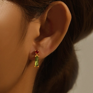 Close-up of S925 silver earrings with red round and green rectangular gems in gold finish