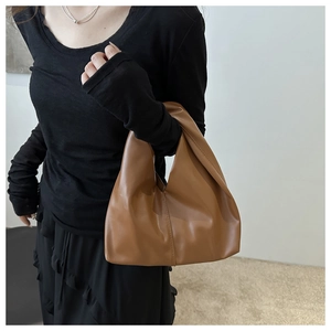 Minimalist brown PU leather tote bag held by model against a neutral aesthetic background
