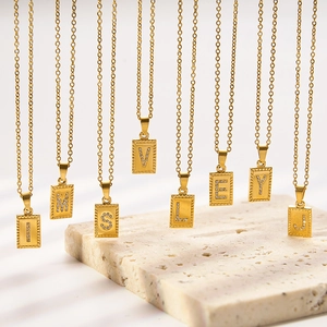 Gold stainless steel necklaces with sparkling crystal alphabet pendants on stone