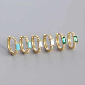 Macro shot of s925 silver gold-plated hoop earrings with emerald and turquoise stones