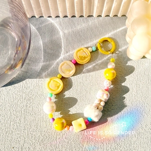 Detailed view of colorful beaded bag charm with plush pompom and yellow bear pendant
