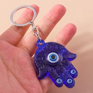 Blue Hamsa Hand and Evil Eye keychain pendant with silver ring held by hand