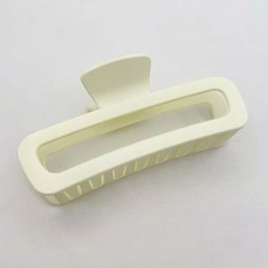 Close-up of matte beige rectangular hair claw clip with strong teeth on fabric