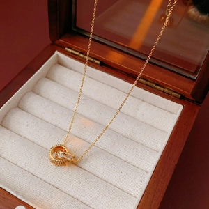 Detailed view of gold double-ring pendant with pavé crystals on a vintage wooden box