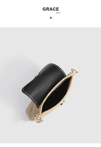 Close-up of woven straw bag showing black leather flap and magnetic metal clasp detail