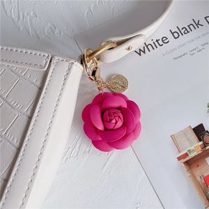 Pink leather camellia flower keychain with gold coin pendant on white crocodile bag