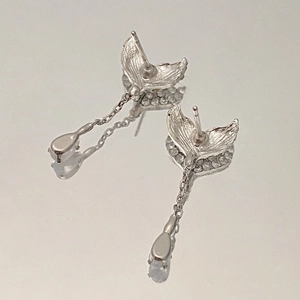 Detailed view of silver mermaid tail earrings with long chains and teardrop gemstones