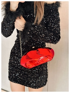 Macro shot of glossy red geometric acrylic clutch bag with metallic gold chain strap