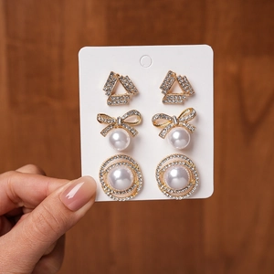 Detail view of 3 pairs of gold-plated earrings with bows, pearls, and rhinestones