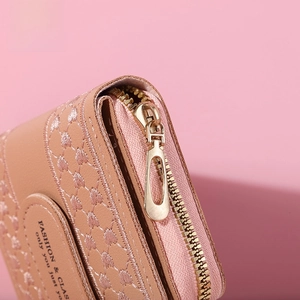 Detail of pink PU leather purse showing heart-shaped quilting and smooth gold zipper