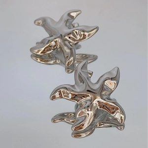 Polished silver starfish stud earrings with a reflective surface in a minimalist style