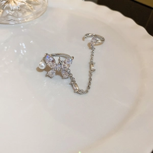 Detail of silver butterfly ring and ear cuff set with pearls and zircon in a ceramic dish