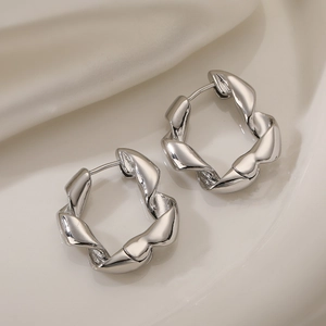 Pendientes geométricos plateados de estilo minimalista y diseño retorcido sobre seda blanca