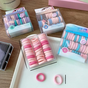 Close-up of macaroon-colored kids hair ties in a compact box with size dimensions