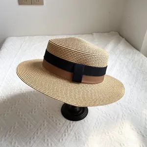 Detailed texture of flat-top straw boater hat with black and brown bi-color ribbon band