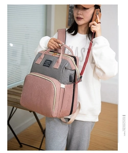 Detail of pink and grey diaper bag showing integrated USB charging port for smartphones