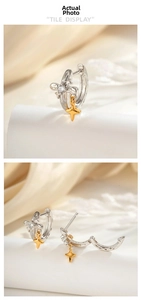 Detailed view of silver hoop earrings with gold star pendants on silk fabric