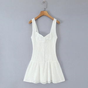 Détail d'une mini robe en dentelle blanche avec décolleté carré et nœud à l'avant